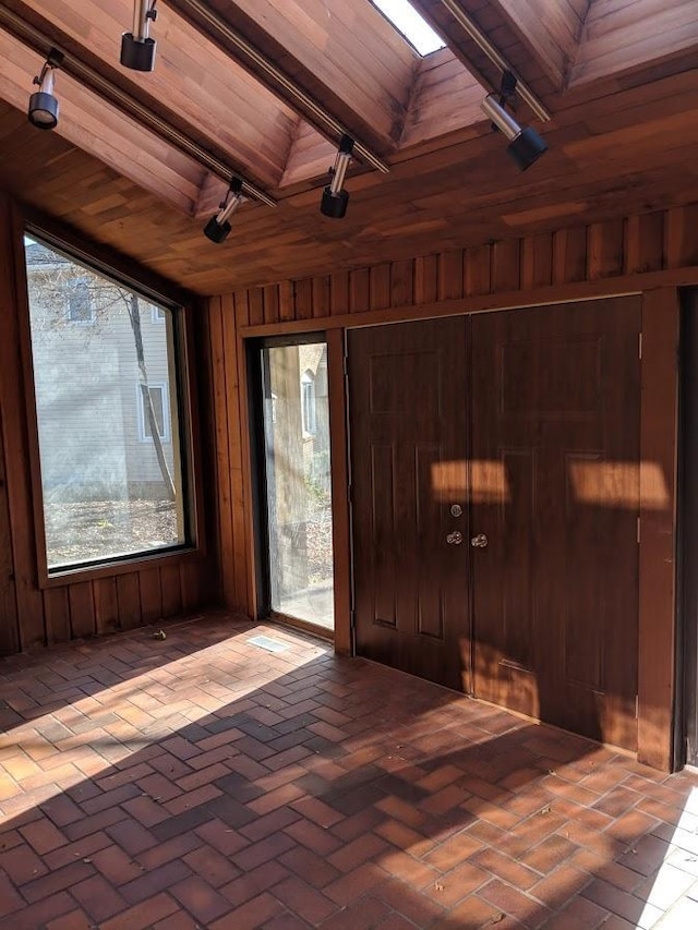 interior space featuring wood ceiling, wooden walls, beamed ceiling, and track lighting