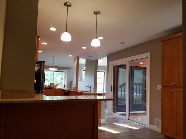 kitchen with fridge, kitchen peninsula, light wood-type flooring, and pendant lighting