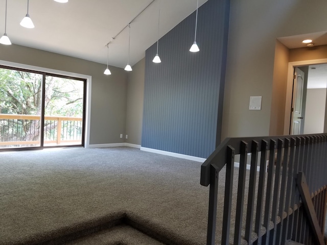 empty room featuring rail lighting, high vaulted ceiling, and carpet