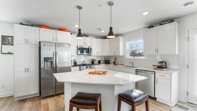 kitchen with a kitchen bar, white cabinetry, and appliances with stainless steel finishes