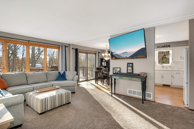 living room with sink, a chandelier, and light colored carpet