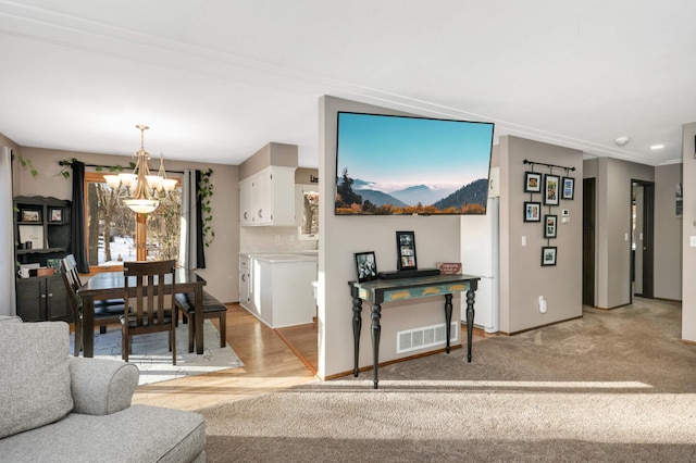 living room featuring crown molding, a chandelier, and light carpet