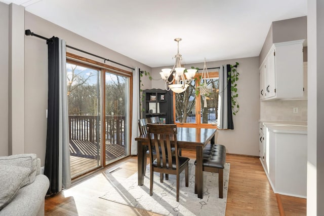 dining room featuring a notable chandelier, light wood-type flooring, and a wealth of natural light