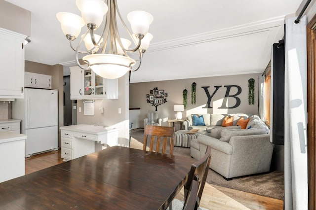 dining space featuring crown molding, a notable chandelier, and light hardwood / wood-style flooring