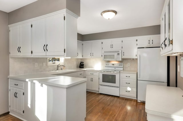 kitchen featuring white appliances, white cabinets, backsplash, and sink