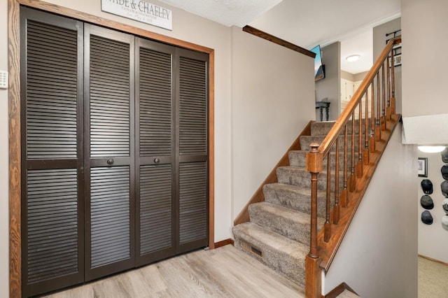 stairway with wood-type flooring and crown molding