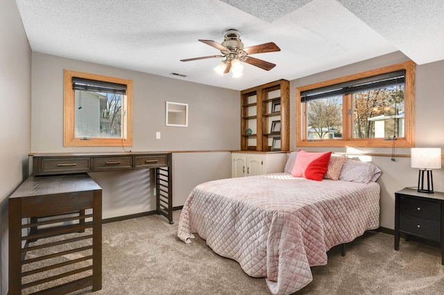 bedroom with a textured ceiling, ceiling fan, and light colored carpet