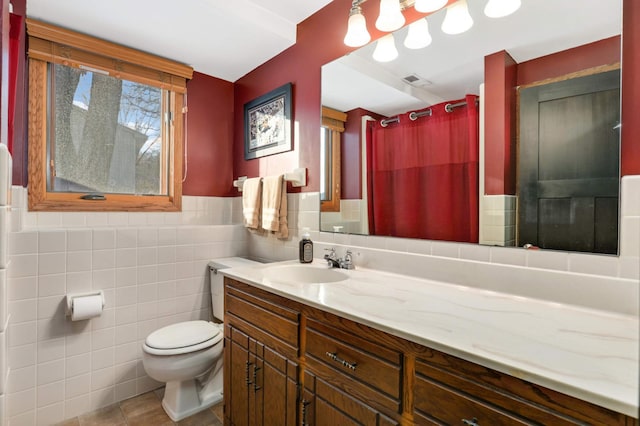 bathroom featuring toilet, tile patterned floors, vanity, tile walls, and curtained shower