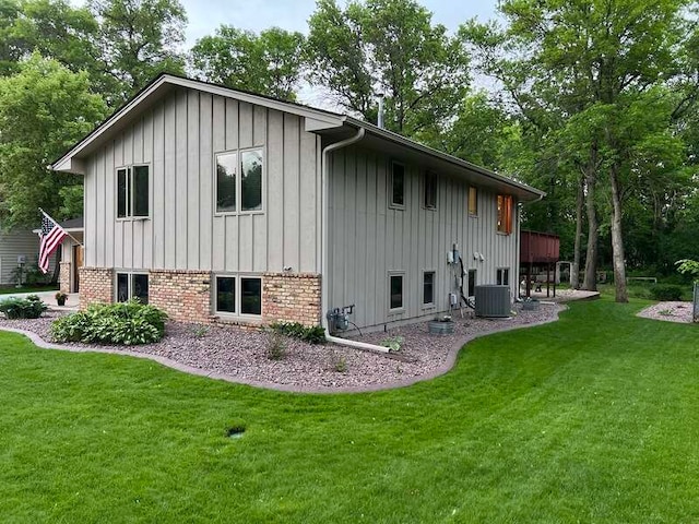 view of side of property featuring central air condition unit and a yard