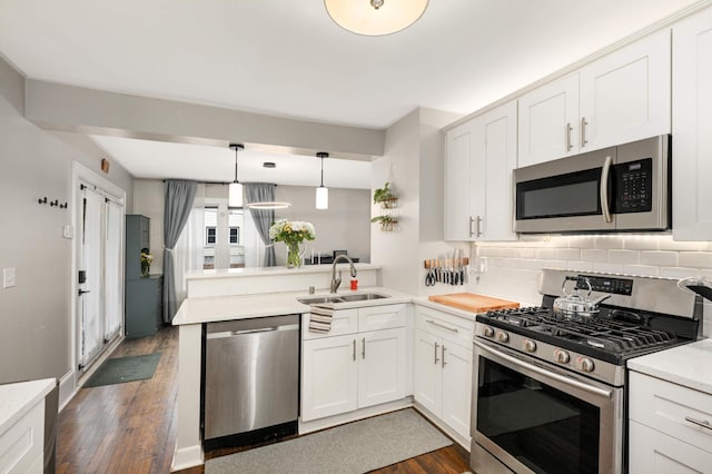 kitchen with sink, decorative light fixtures, white cabinetry, kitchen peninsula, and appliances with stainless steel finishes