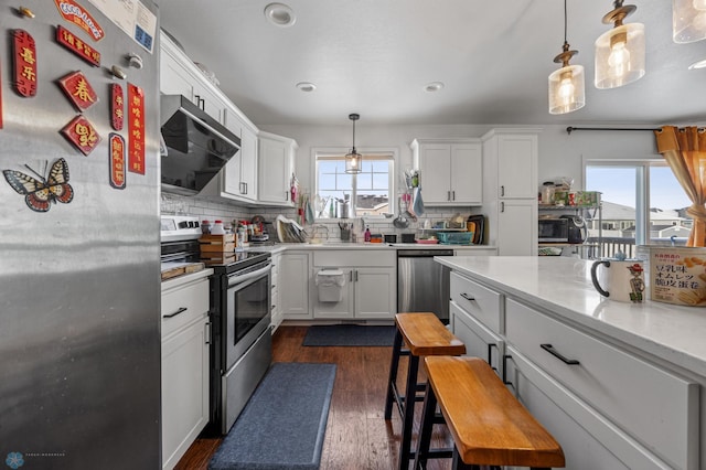 kitchen with stainless steel appliances, white cabinets, pendant lighting, and ventilation hood