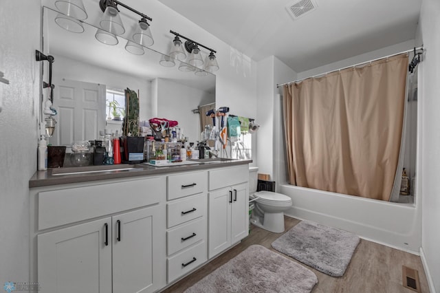 full bathroom featuring toilet, shower / bath combo with shower curtain, wood-type flooring, and vanity