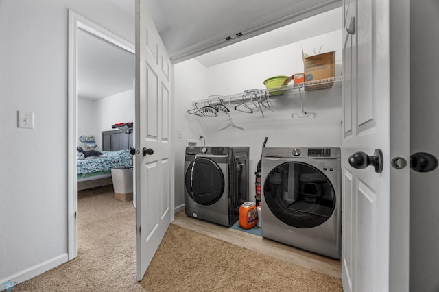 clothes washing area featuring washer and clothes dryer and light carpet