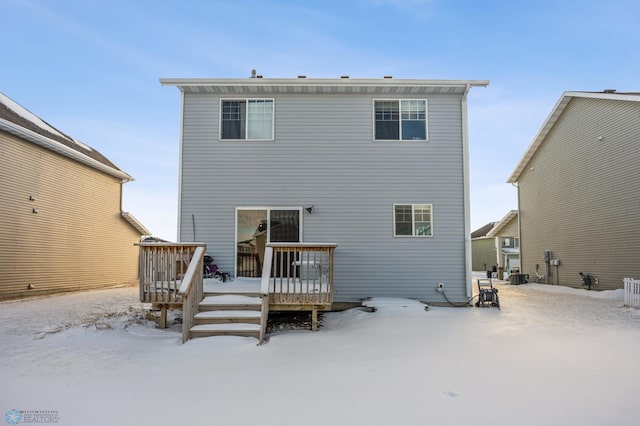 snow covered back of property featuring a wooden deck and central air condition unit