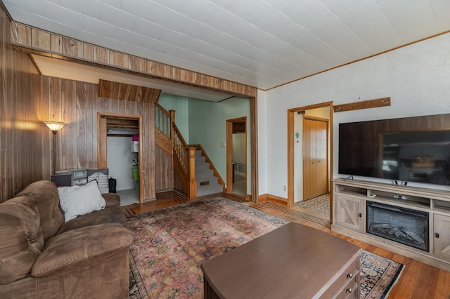 living room featuring light wood-type flooring, a fireplace, and wood walls