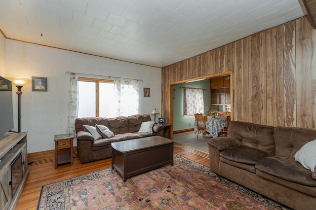 living room featuring light hardwood / wood-style floors, crown molding, and wooden walls