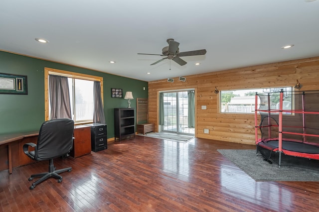 office area featuring ceiling fan, dark hardwood / wood-style floors, and wood walls