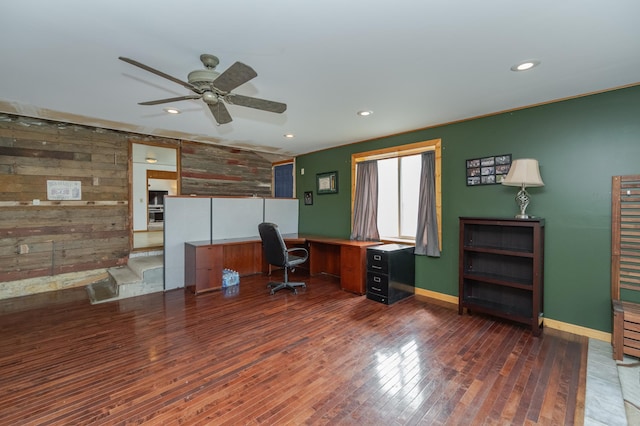 home office featuring ceiling fan, dark hardwood / wood-style flooring, and wooden walls