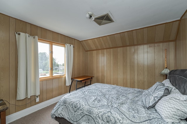 bedroom with vaulted ceiling, wood walls, and carpet flooring