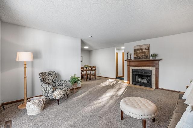 living room with a textured ceiling, carpet flooring, and a tile fireplace