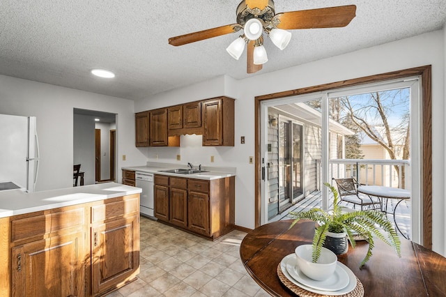 kitchen with dishwasher, sink, white fridge, and a textured ceiling