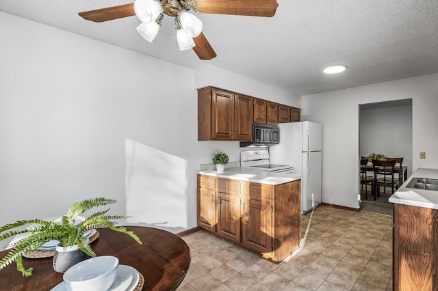 kitchen featuring a textured ceiling, ceiling fan, sink, and white appliances