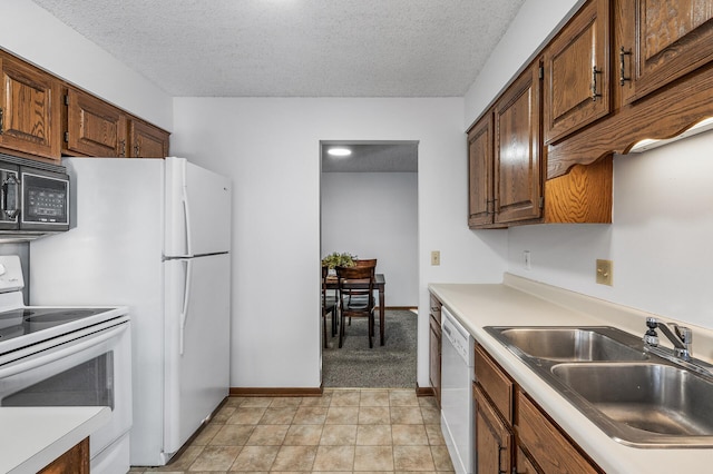 kitchen featuring sink, white appliances, and a textured ceiling