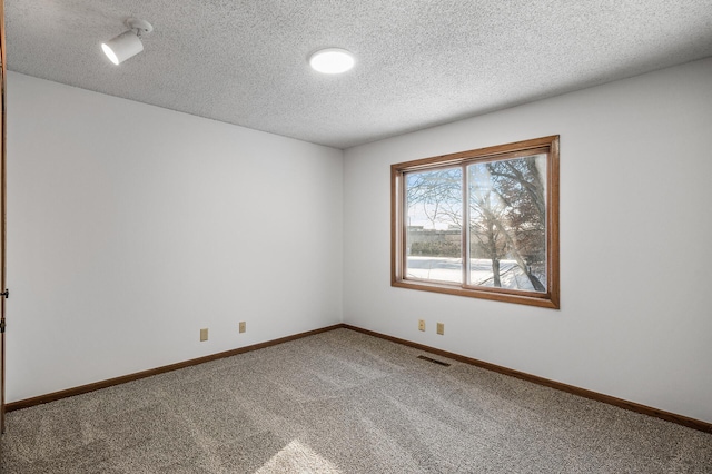 empty room with carpet floors and a textured ceiling