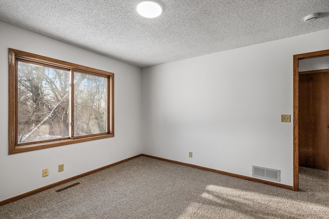 unfurnished room with a textured ceiling and carpet flooring