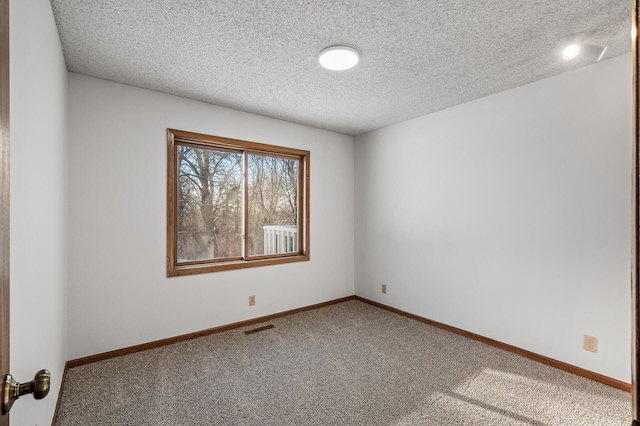 carpeted empty room featuring a textured ceiling