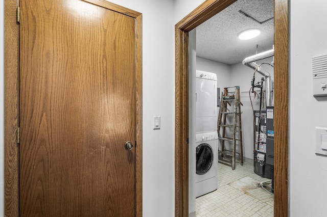 clothes washing area with a textured ceiling and stacked washer / dryer