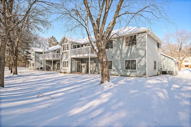 snow covered back of property featuring a balcony