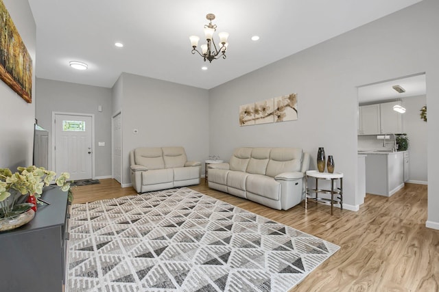 living room with light wood-type flooring, a chandelier, and sink