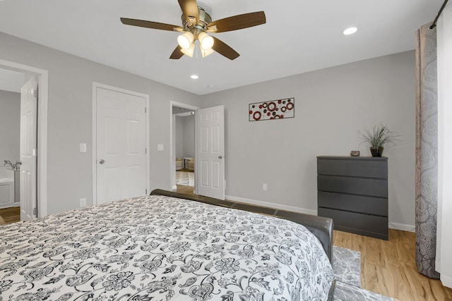 bedroom featuring ceiling fan, ensuite bath, and light hardwood / wood-style flooring