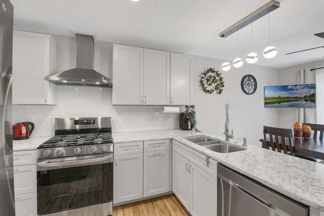 kitchen with white cabinets, appliances with stainless steel finishes, wall chimney exhaust hood, and sink