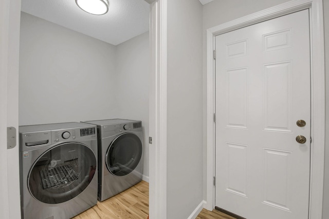 laundry room featuring washing machine and clothes dryer and hardwood / wood-style flooring