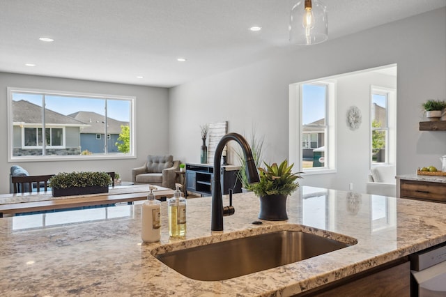 kitchen featuring light stone counters, sink, and dishwasher