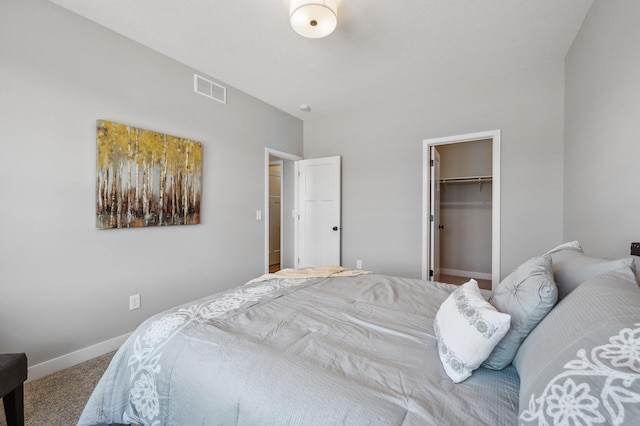 carpeted bedroom featuring a walk in closet and a closet