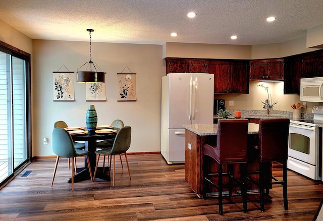 kitchen featuring white appliances, dark hardwood / wood-style floors, hanging light fixtures, and a center island