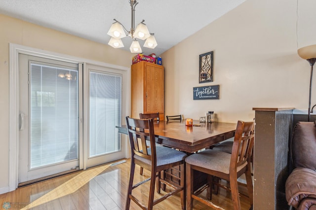 dining room featuring a textured ceiling, light hardwood / wood-style floors, and a notable chandelier