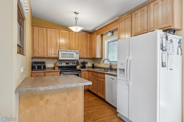 kitchen featuring sink, decorative light fixtures, lofted ceiling, light hardwood / wood-style floors, and appliances with stainless steel finishes