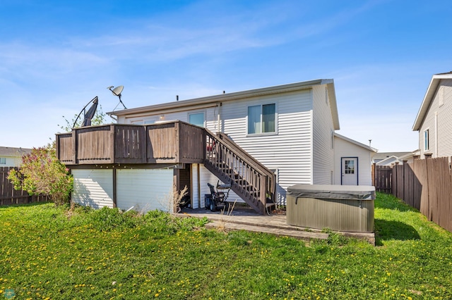 back of property with a hot tub, a wooden deck, and a yard