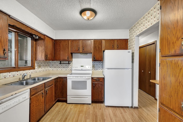 kitchen featuring white appliances, light wood-type flooring, a textured ceiling, and sink