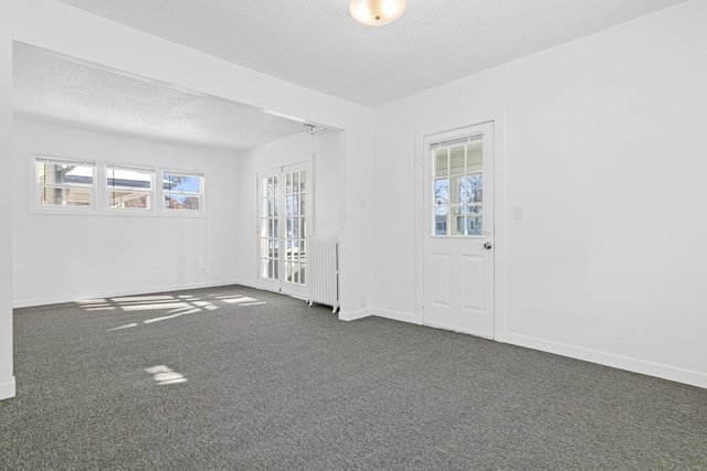 carpeted empty room featuring french doors and radiator heating unit