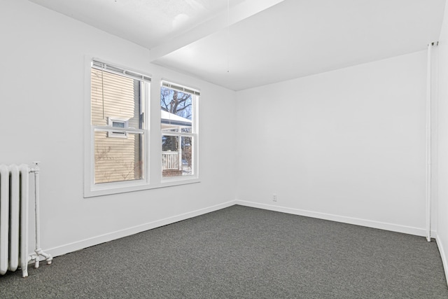 empty room featuring dark carpet and radiator heating unit