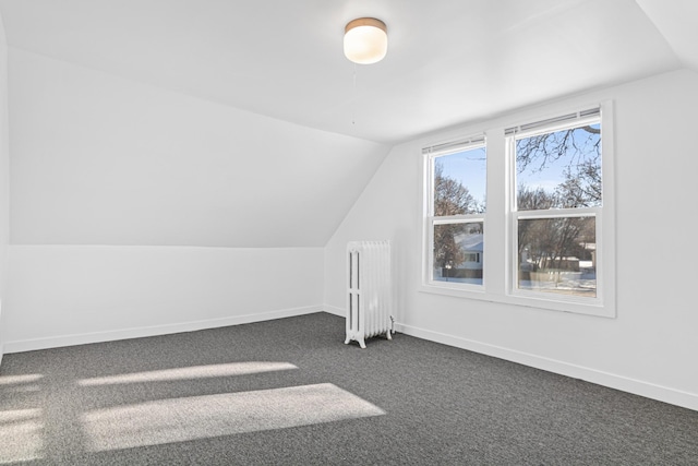 bonus room with vaulted ceiling, radiator heating unit, and dark colored carpet