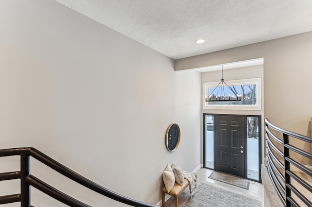 foyer entrance with a towering ceiling, an inviting chandelier, and a textured ceiling