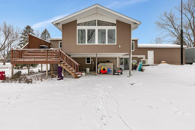 snow covered back of property with a wooden deck