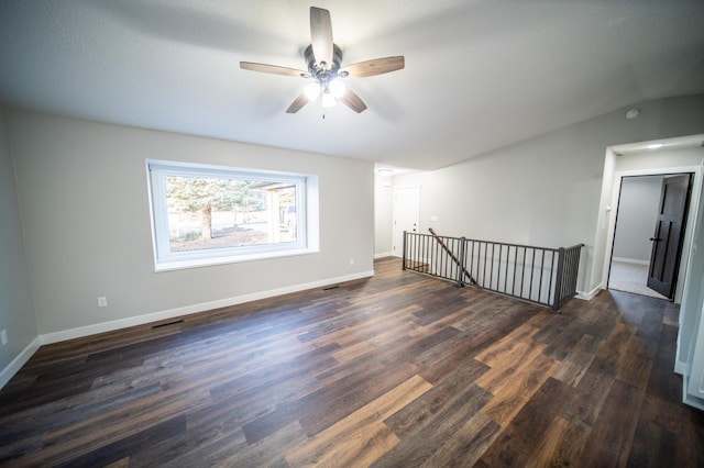 empty room featuring ceiling fan, vaulted ceiling, and dark hardwood / wood-style floors