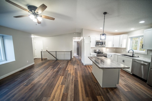 kitchen with lofted ceiling, a center island, sink, white cabinetry, and stainless steel appliances